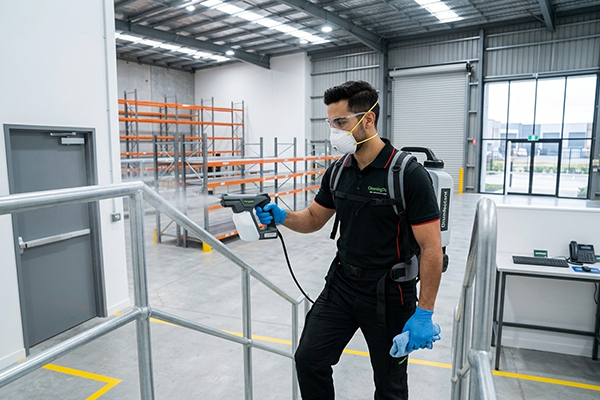 Commercial cleaner disinfecting warehouse handrails and high touch areas